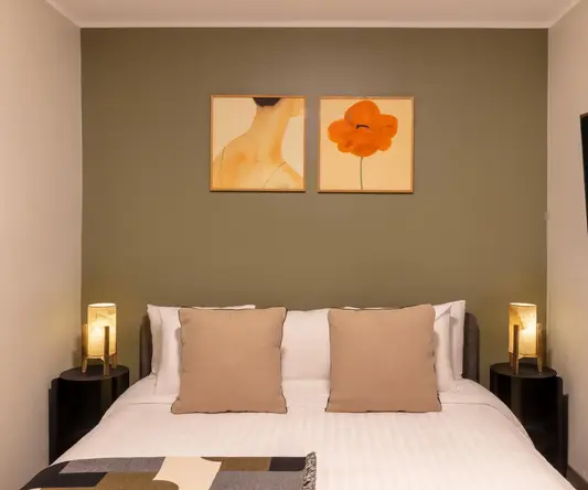 a bed with two lamps on the wall
