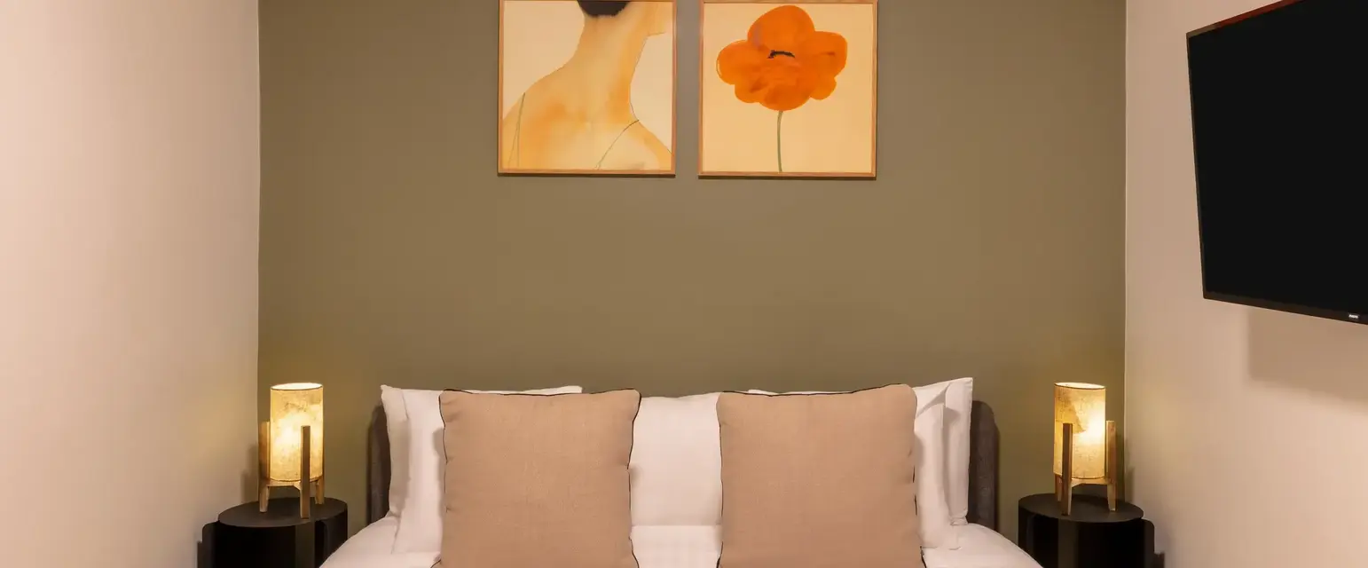 a bed with two lamps on the wall