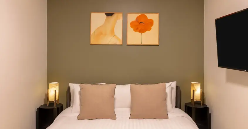 a bed with two lamps on the wall