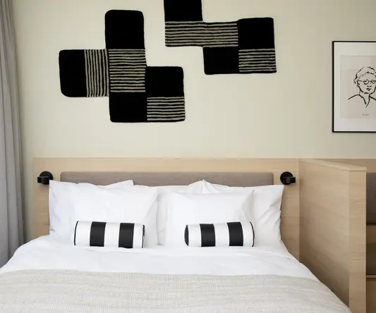 a bed with pillows and a black and white pillow on the headboard