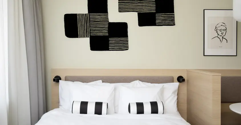 a bed with pillows and a black and white pillow on the headboard