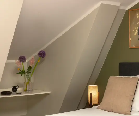 a bed with a lamp and a picture on the wall