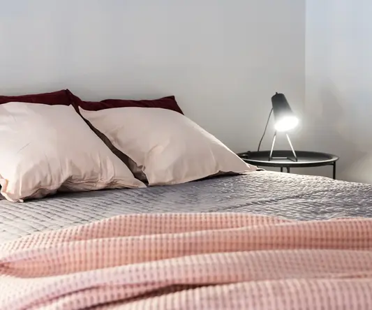 a bed with pillows and a pink blanket