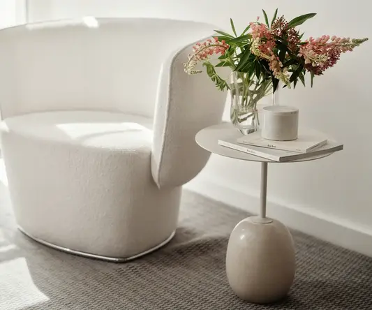 a white chair with a vase of flowers on a table