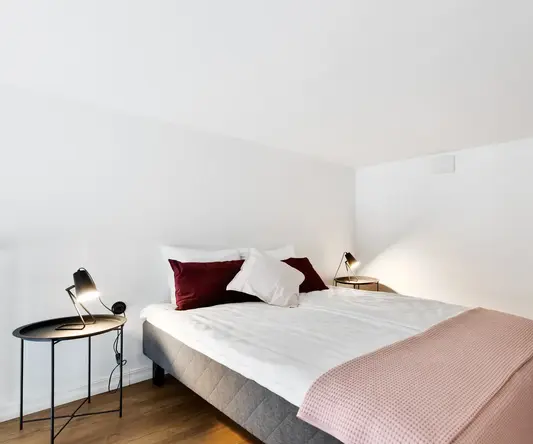 a bed with pillows and a lamp in a room