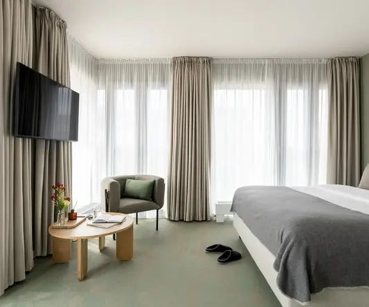 a room with a bed and a chair and a television