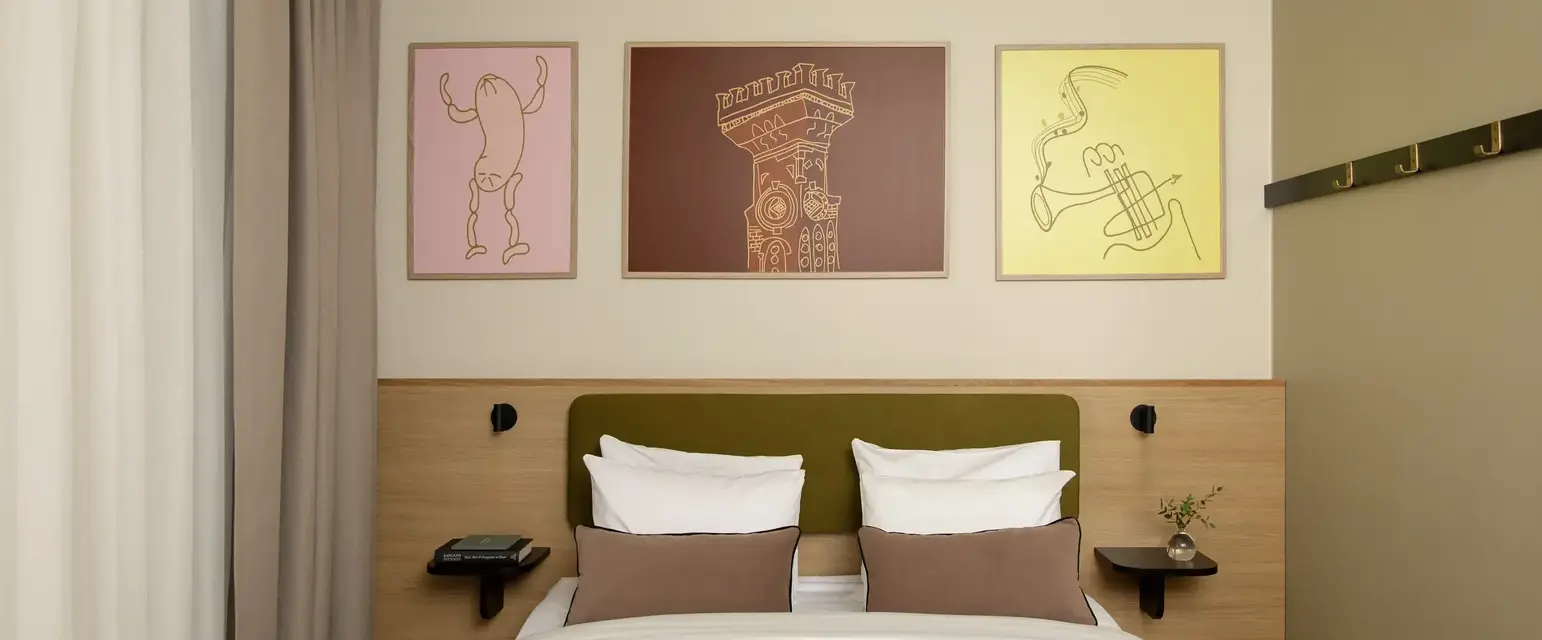 a bed with pillows and a table with artwork above it