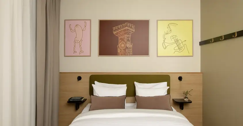 a bed with pillows and a table with artwork above it
