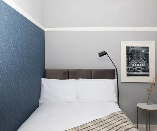 a bed with a lamp and a picture on the wall