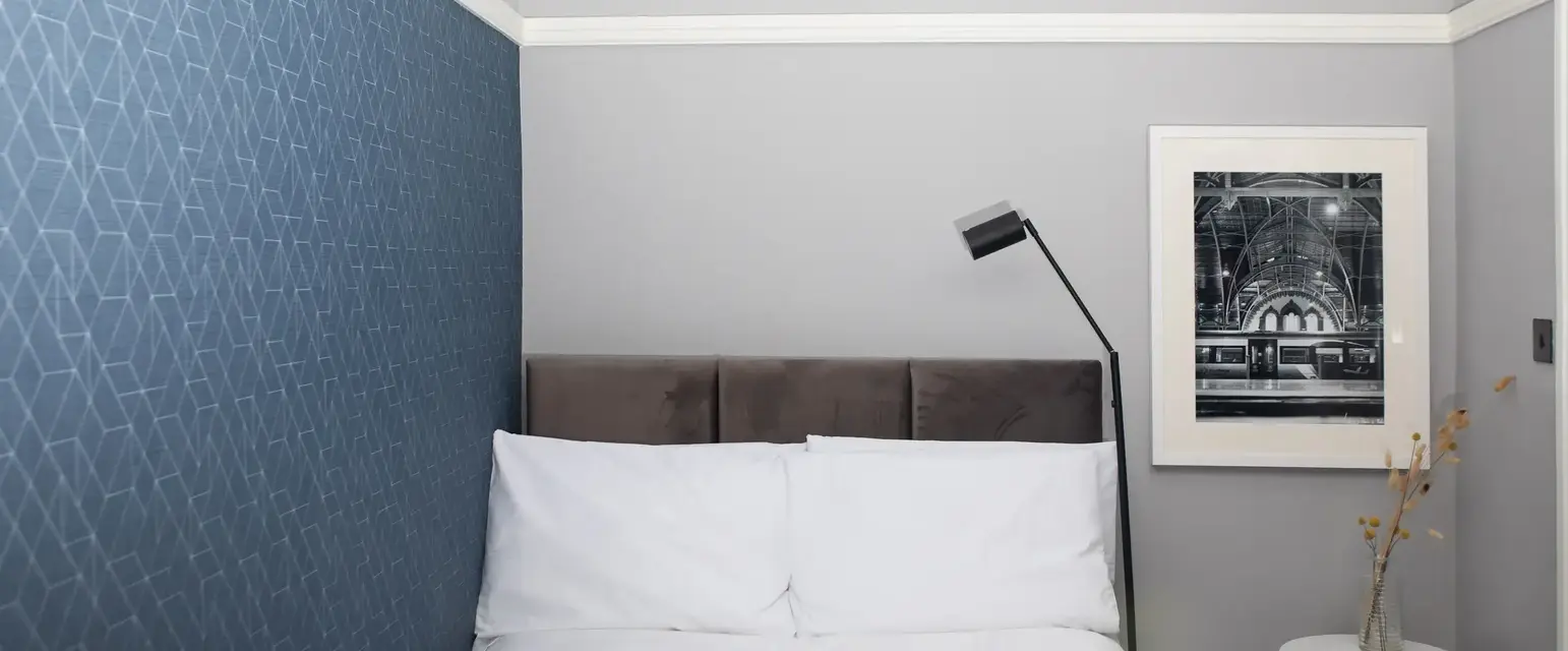 a bed with a lamp and a picture on the wall