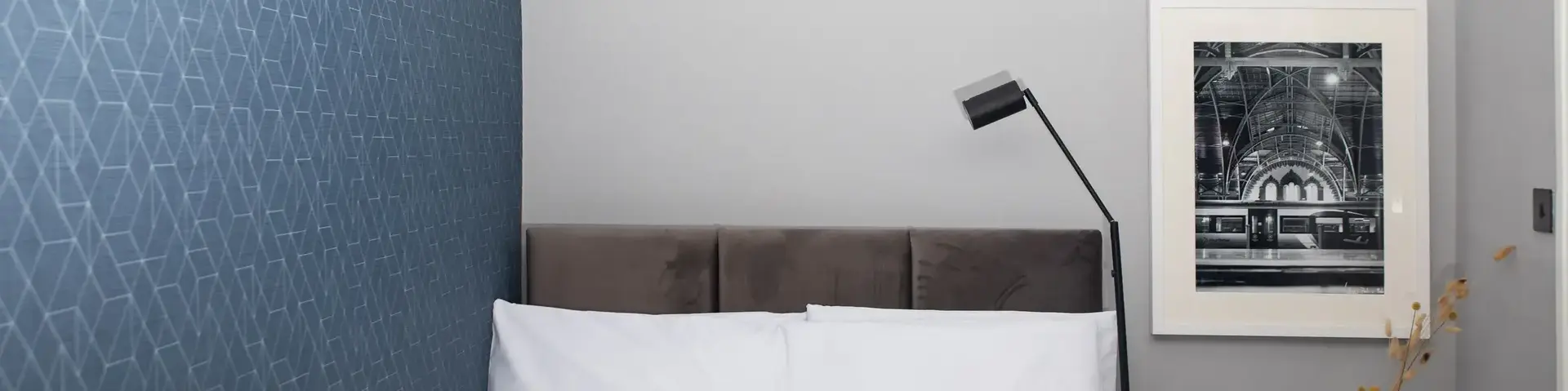 a bed with a lamp and a picture on the wall