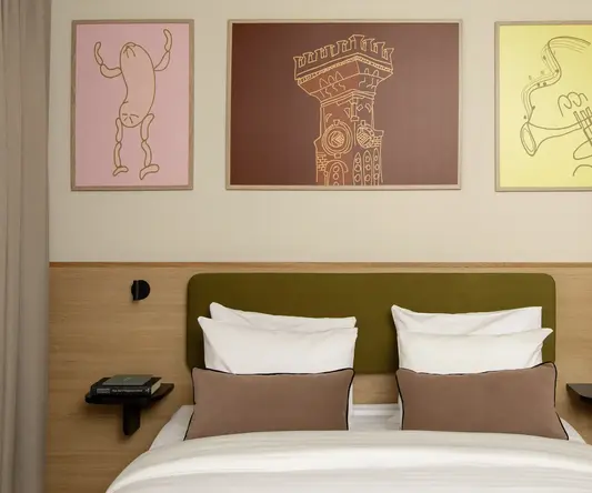 a bed with pillows and a table with artwork on the wall