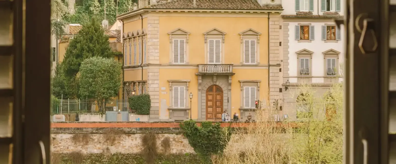 a window with a yellow building and trees in the background