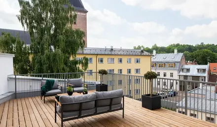 a deck with a couch and a table and planter on it