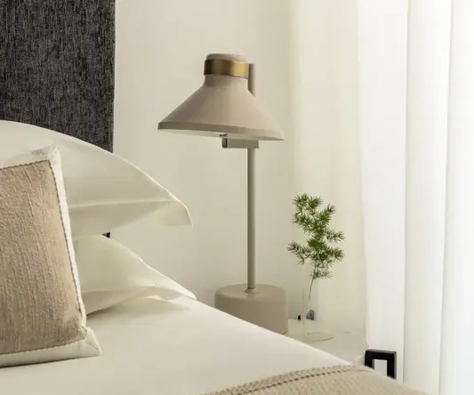 a lamp on a table next to a bed