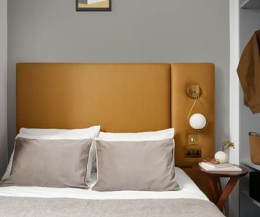 a bed with pillows and a lamp on the side of it