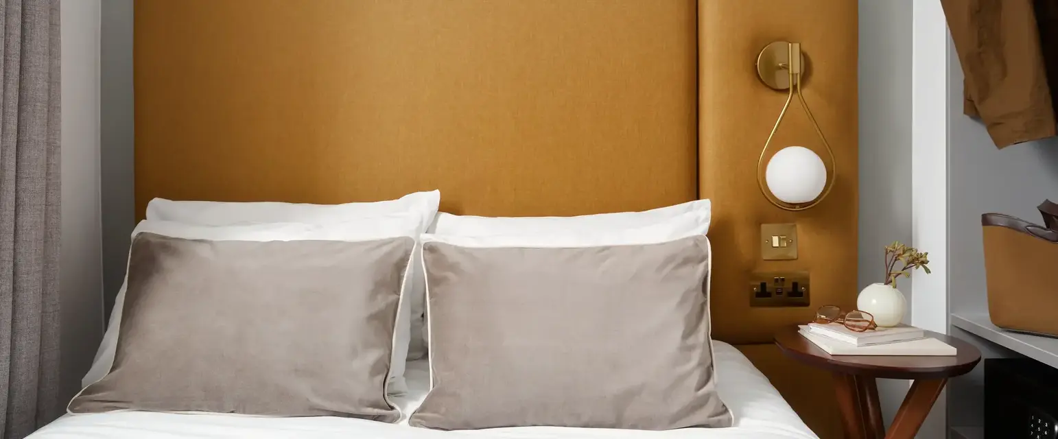 a bed with pillows and a lamp on the side of it