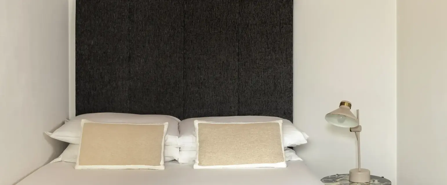 a bed with pillows and a lamp on the side of the bed