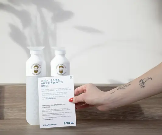 a hand holding a piece of paper next to bottles of shampoo