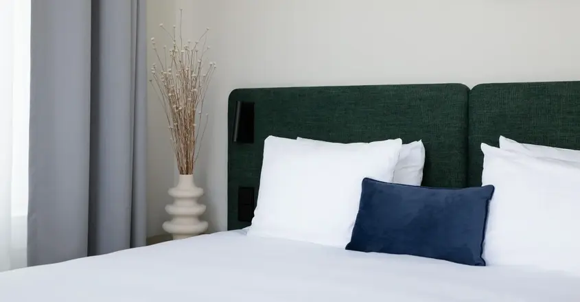 a bed with white sheets and pillows