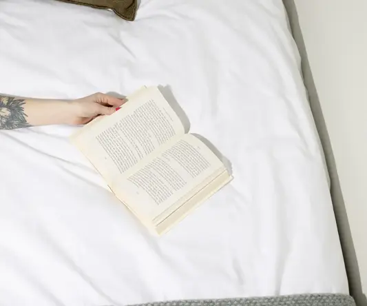 a person reading a book on a bed
