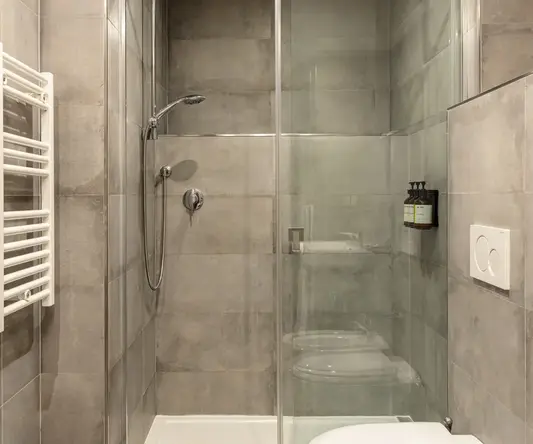 a shower with a toilet and a glass door