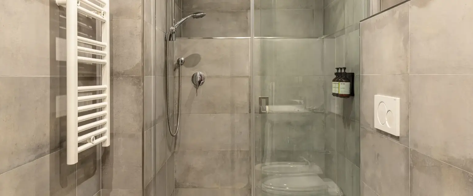 a shower with a toilet and a glass door