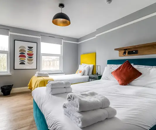 a room with two beds and a bed with towels