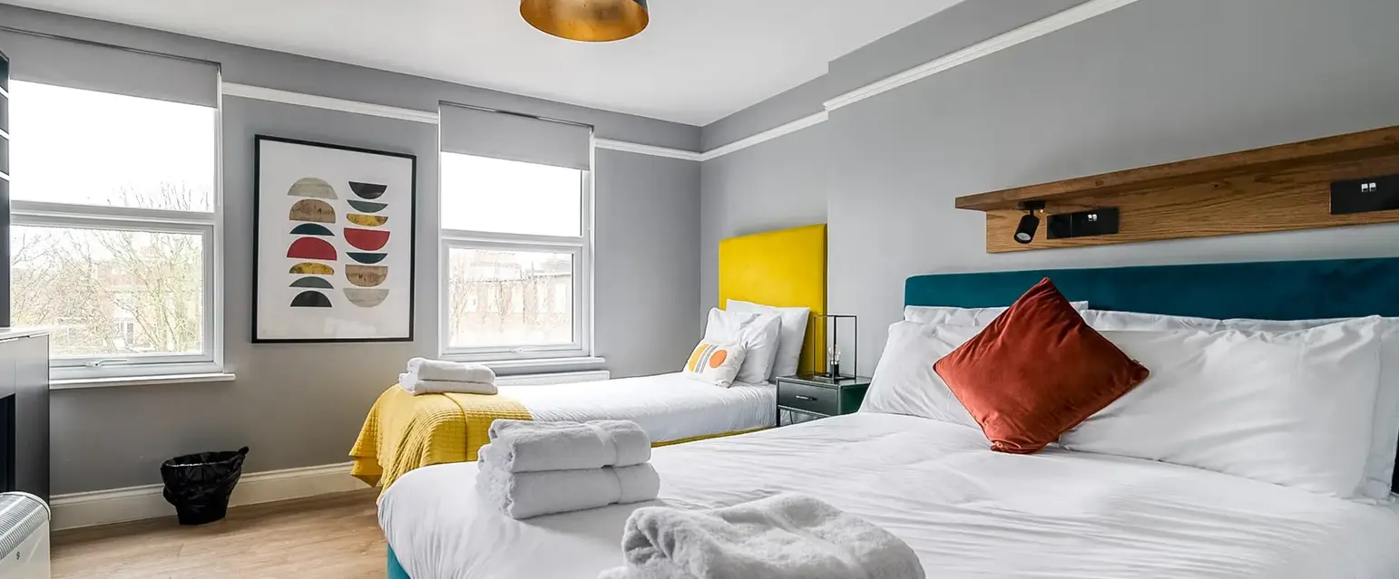 a room with two beds and a bed with towels