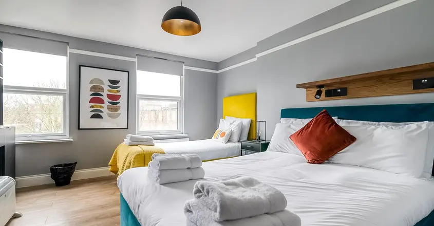 a room with two beds and a bed with towels