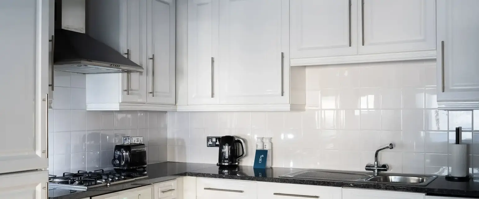 a kitchen with white cabinets and black counter tops