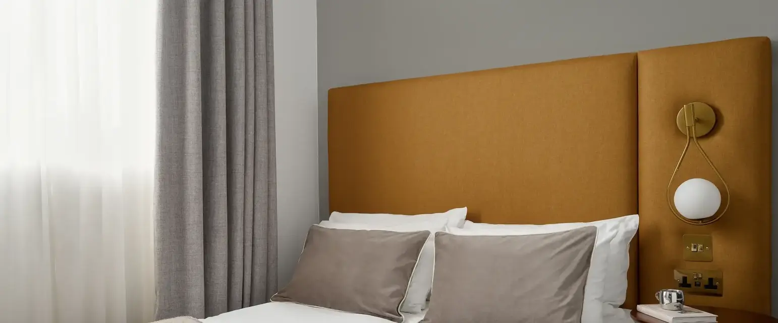 a bed with a brown headboard and a lamp on the side