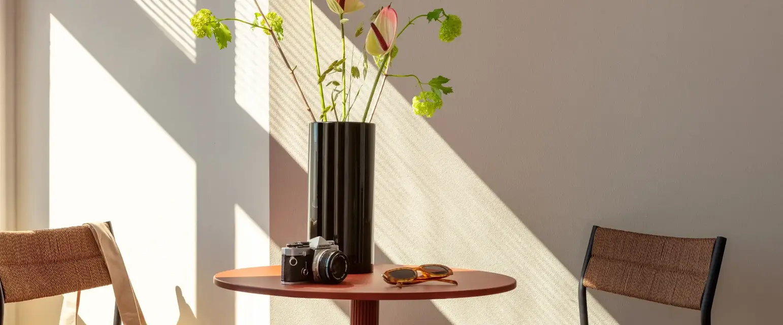 a vase with flowers and sunglasses on a table