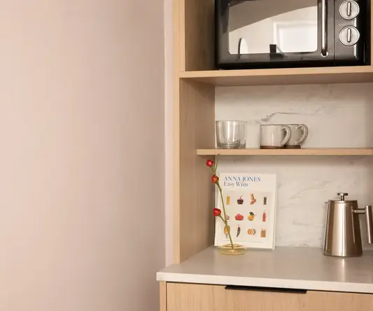 a shelf with a microwave and mugs on it