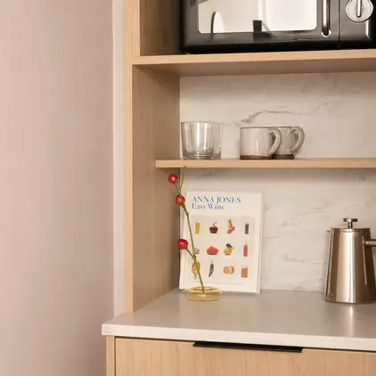 a shelf with a microwave and mugs on it