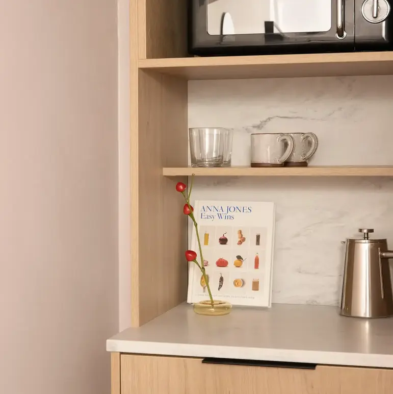 a shelf with a microwave and mugs on it