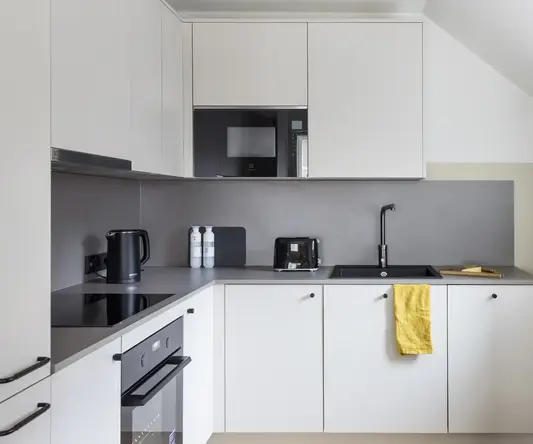 a kitchen with white cabinets and black appliances