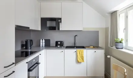 a kitchen with white cabinets and black appliances
