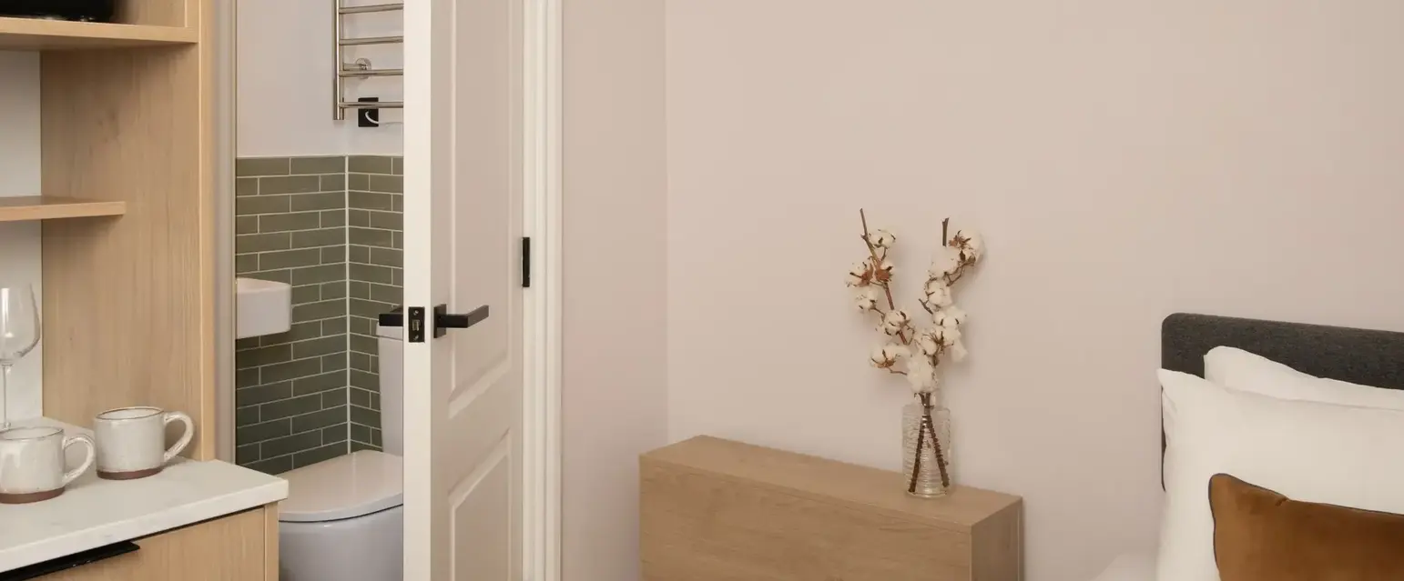 a bedroom with a white bed and a wood dresser