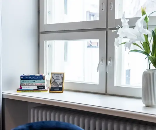 a white vase with white flowers and a white vase on a window sill
