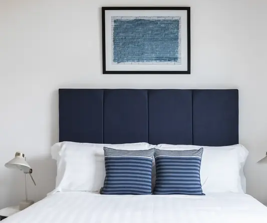 a bed with pillows and a picture above it