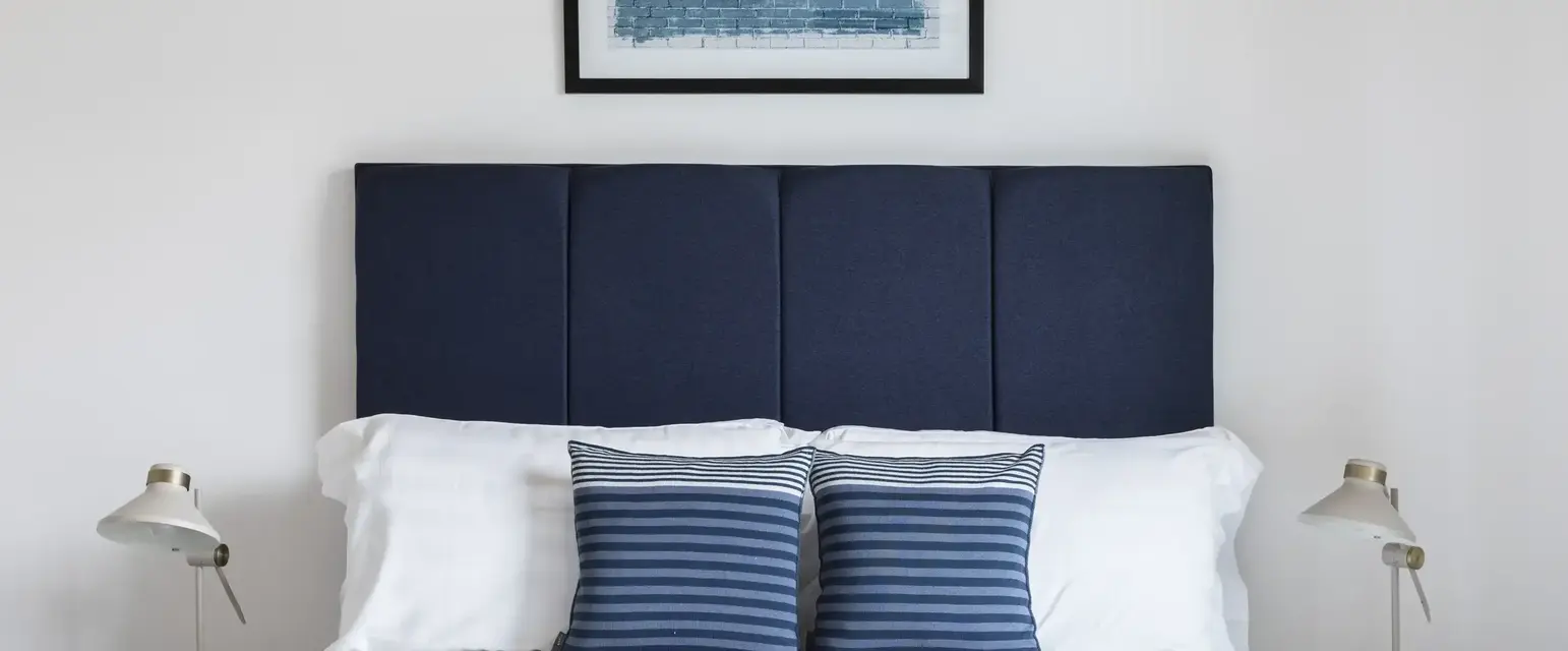 a bed with pillows and a picture above it