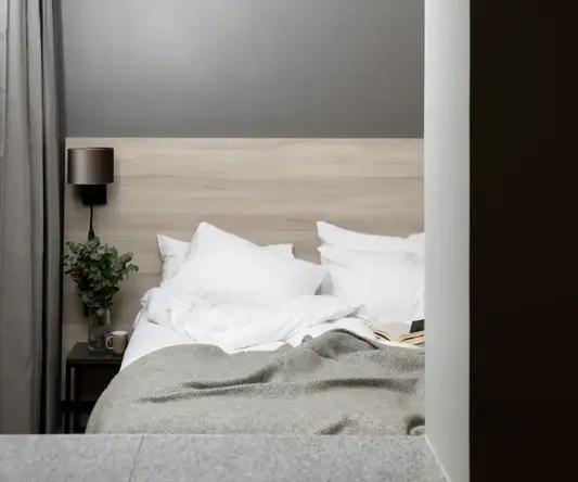 a bed with pillows and a plant on the side