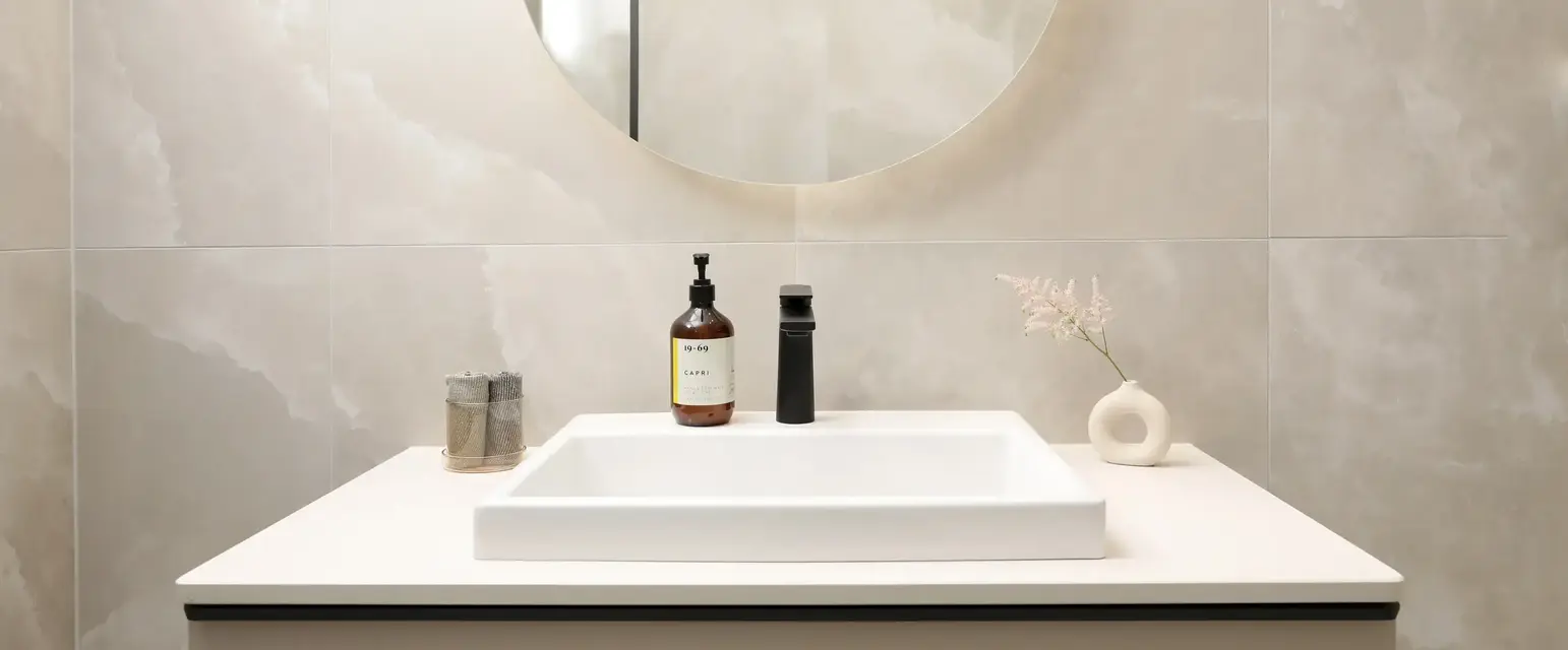 a bathroom sink with a round mirror