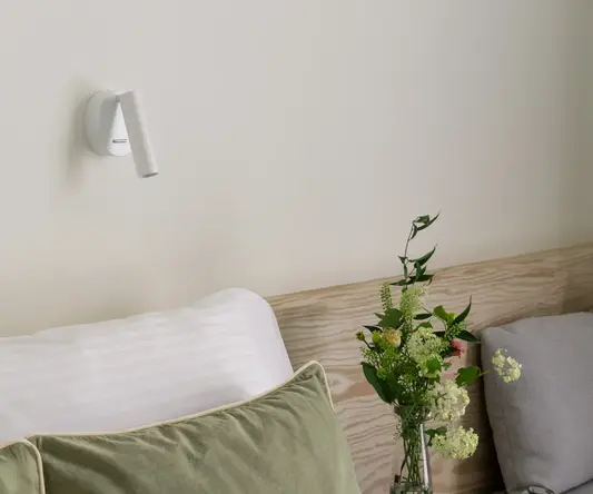 a bed with pillows and a vase of flowers