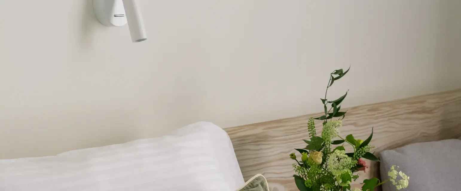 a bed with pillows and a vase of flowers