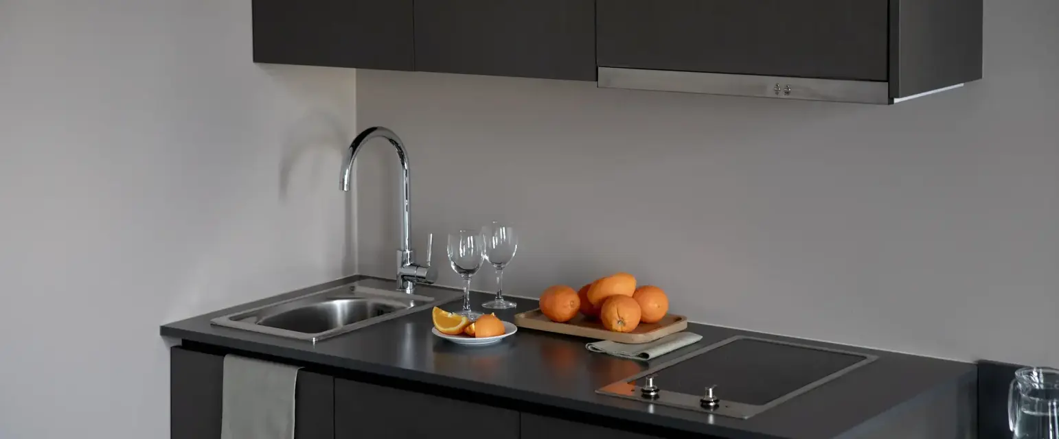 a kitchen counter with a sink and a tray of oranges