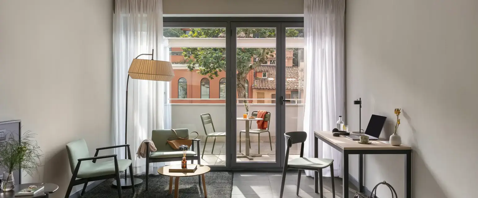 a room with a desk and chairs and a table and a glass door