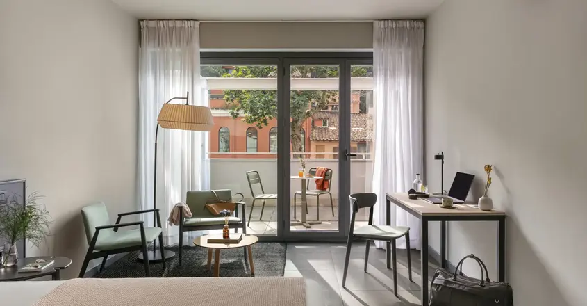 a room with a desk and chairs and a table and a glass door