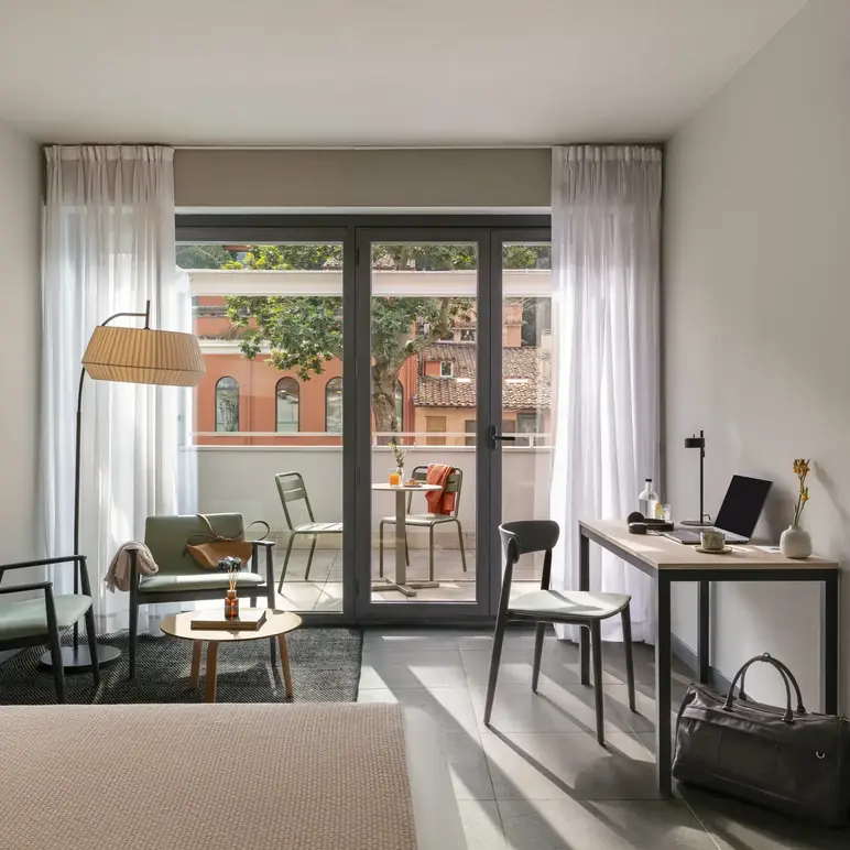 a room with a desk and chairs and a table and a glass door